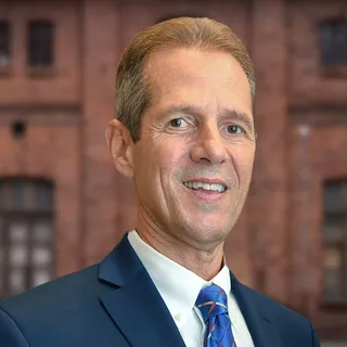 John Cranias, Settlement Consultant at Brant Hickey Orlando, standing in front of a brick wall
