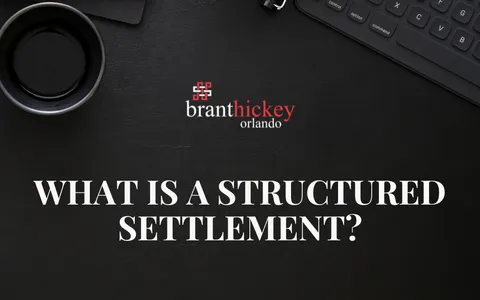 A notepad reading "What is a structured settlement?" beside a pen and calculator